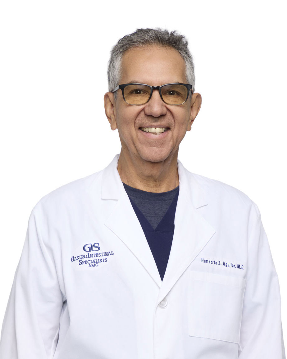 A man wearing glasses and a white lab coat with the logo "GastroIntestinal Specialists" stands smiling against a plain white background.